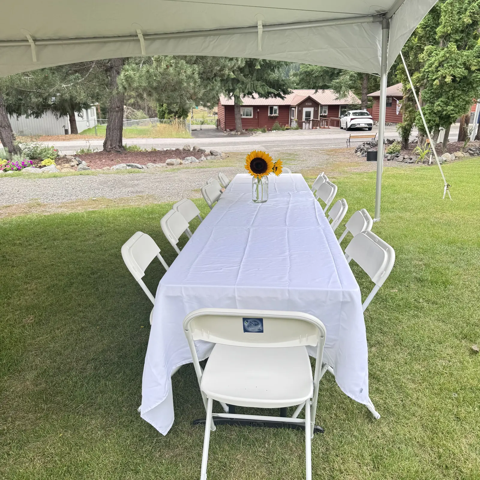 White-covered tables and chairs arranged beneath an outdoor tent